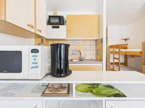 une cuisine avec un micro-ondes et un plan de travail dans l'établissement Appartement T2 cabine climatisé, à 400m de la plage, proche commerces, 2ème étage, parking inclus - FR-1-423-272, au Grau-dʼAgde