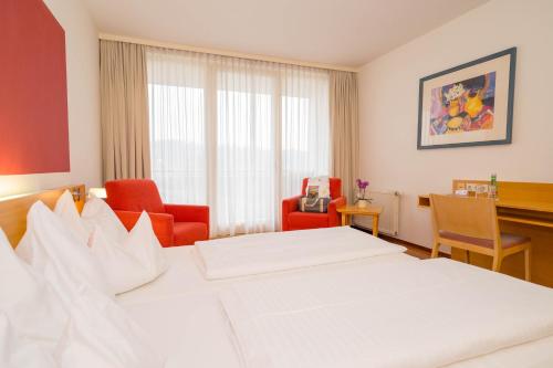 a hotel room with a bed and two chairs and a desk at Allegria Resort Stegersbach - Allegria Hotel in Stegersbach