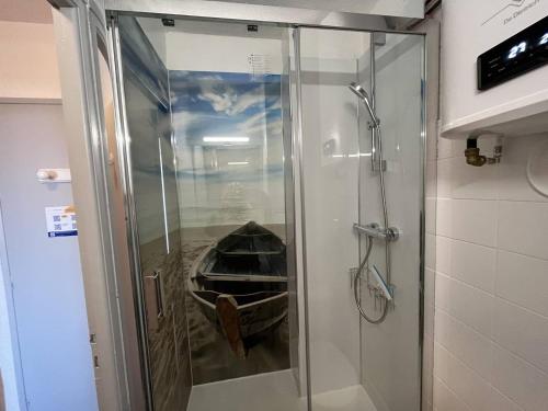 une douche avec une porte vitrée dans une salle de bain dans l'établissement Studio naturiste bord de mer, terrasse sud, clim, parking - FR-1-249A-44, au Cap d'Agde