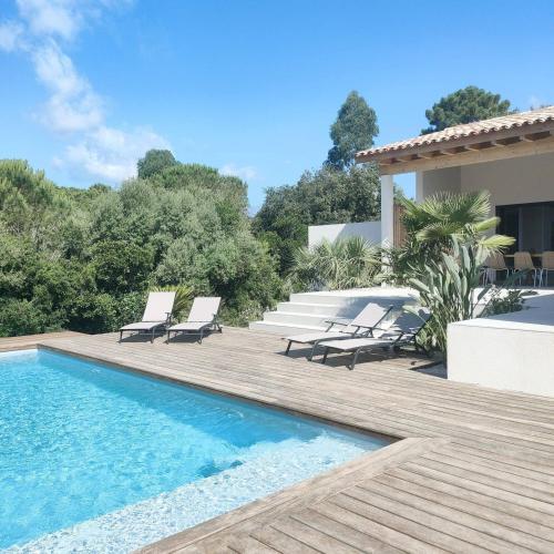 - une piscine avec 2 chaises longues et une maison dans l'établissement suara, à Pinarellu