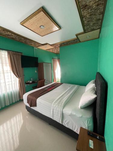 a bedroom with a large bed with green walls at Solaris Malioboro in Jetis