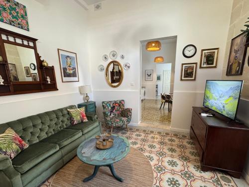 a living room with a green couch and a table at Central Boutique Apartment Near Valletta - Perfect Location to Discover Malta - Bus Stops Just Outside & Adjoining Cafeteria in Msida