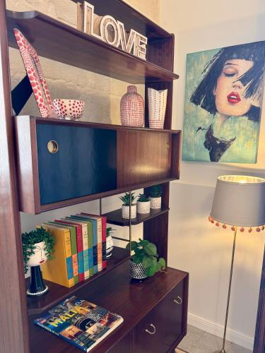 a book shelf with a tv in a living room at Central Boutique Apartment Near Valletta - Perfect Location to Discover Malta - Bus Stops Just Outside & Adjoining Cafeteria in Msida