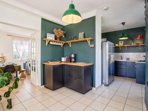 une cuisine avec des placards bleus et des murs verts dans l'établissement Maison familiale avec sauna et ferme proche plage - FR-1-788-49, à Gonneville-en-Auge