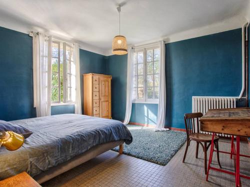 - une chambre avec des murs bleus, une table et un lit dans l'établissement Maison familiale avec sauna et ferme proche plage - FR-1-788-49, à Gonneville-en-Auge