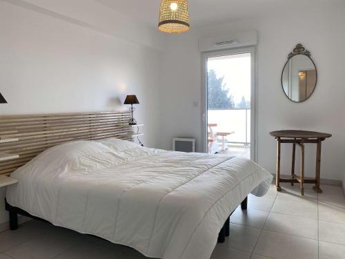 une chambre avec un lit, une table et un miroir dans l'établissement Appartement T3 moderne avec terrasse et parking sécurisé - FR-1-553-293, à Balaruc-les-Bains