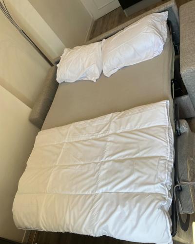 Ce lit se trouve dans une petite chambre dotée de draps blancs. dans l'établissement Charming studio in a good location, à Vallauris