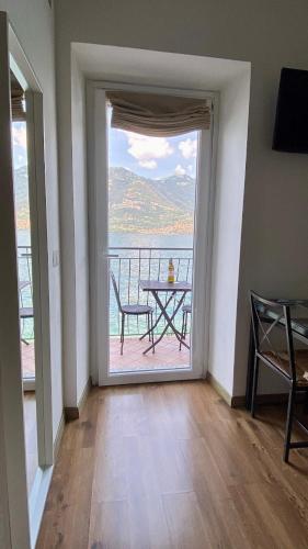 a room with a table and a balcony with a view at B&B Nest on the Lake in Lezzeno
