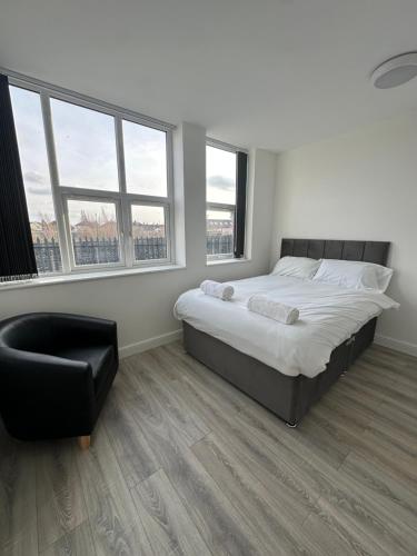 a bedroom with a bed and a chair and windows at 2 Bed Sizeable Station House Apartment - Free Wifi, Parking & EV in Scunthorpe