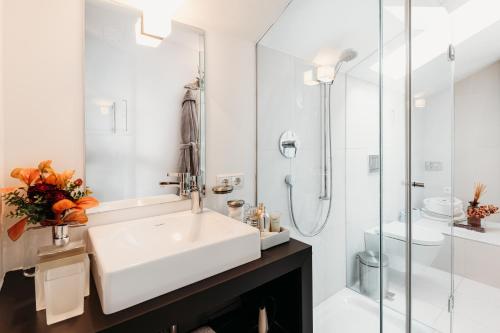 a white bathroom with a sink and a shower at Loft Thaler Rooms in Bolzano