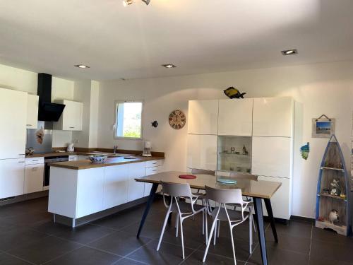 une cuisine avec des armoires blanches et une table et des chaises dans l'établissement t3cj n14, à Pinarellu