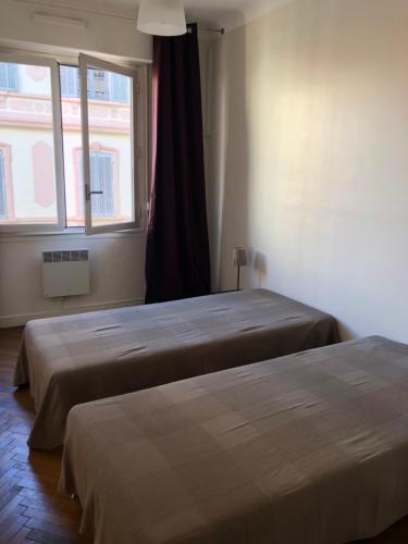 deux lits dans une chambre avec une fenêtre dans l'établissement merimée 4G, à Cannes