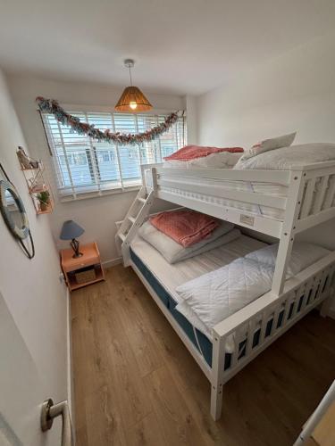 two bunk beds in a room with a window at 288, Two bed Chalet on Belle Aire Holiday Park - With private veranda, sleeps 5, pet friendly, free Wi-Fi, bed linen and towels included and onsite entertainment available in Hemsby
