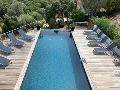 une piscine avec des chaises longues et une terrasse en bois dans l'établissement Rostalana, à Pinarellu