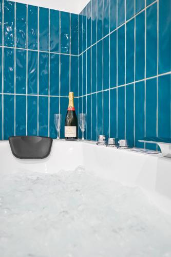 - une bouteille de vin et deux verres dans la baignoire dans l'établissement Le Sweet - Love Room - Jacuzzi - Wifi, à Montry