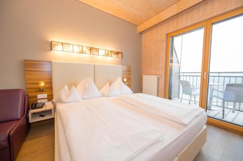 a large white bed in a room with a balcony at Allegria Resort Stegersbach - Allegria Hotel in Stegersbach