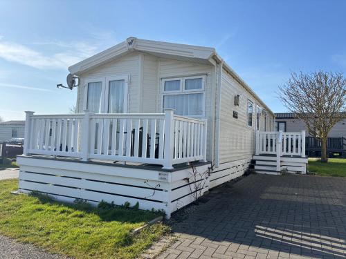 a tiny house with a white railing and a porch at 64, Belle Aire Caravan Park, Sleeps 6, Bed Linen and Towels Included, Free WiFi, Pets Welcome with onsite clubhouse in Great Yarmouth