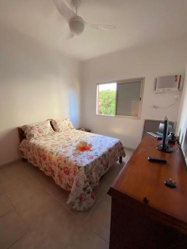 a bedroom with a bed and a desk with a computer at Enseada Malibu perto da praia, lazer e conforto! in Guarujá