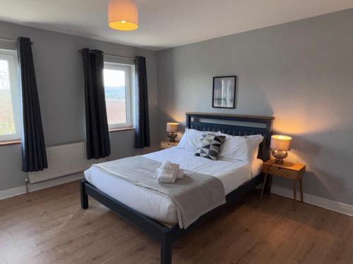 a bedroom with a bed with two lamps and two windows at An Teach Bábóige - The Doll house - Kildare in Kildare