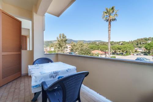 a balcony with a table and chairs and a palm tree at Appartamenti Gli Orizzonti - Goelba in Marina di Campo