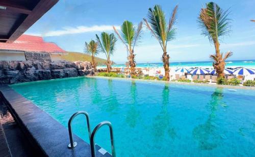 ein Swimmingpool mit Palmen und dem Meer in der Unterkunft The Sky & Sea Koh Larn in Ko Larn