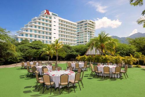 a group of tables and chairs on a lawn with a building at Santa Marta Marriott Resort Playa Dormida in Santa Marta
