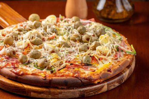 a pizza sitting on top of a wooden table at Marambaia Hotel e Convenções in Balneário Camboriú