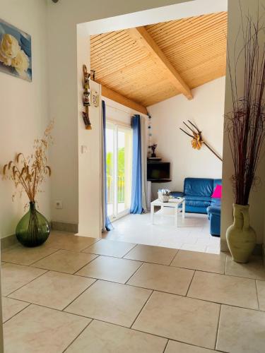 a living room with a blue couch and a wooden ceiling at Gite - Vue imprenable - Pisicine - Vezac in Vézac