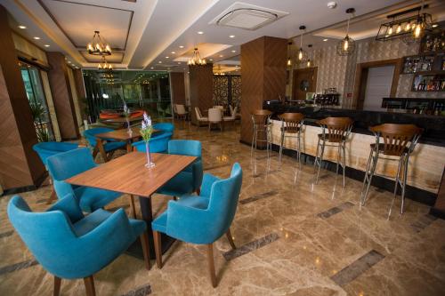 a restaurant with blue chairs and tables and a bar at Görükle Güler Park Hotel in Gorukle