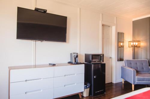 a room with a dresser with a tv and a chair at Riôtel Carleton-sur-Mer in Carleton sur Mer