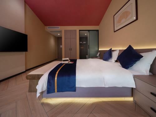a large bedroom with a large bed and a flat screen tv at Yun Guan Shunde Renjia Resort Hotel in Jinghong