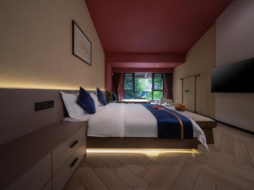 a large bedroom with a large bed with a television at Yun Guan Shunde Renjia Resort Hotel in Jinghong