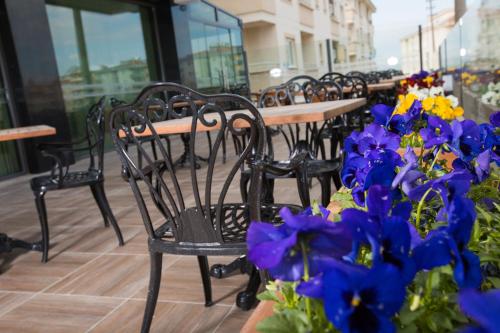 a row of tables and chairs with purple and blue flowers at Görükle Güler Park Hotel in Gorukle