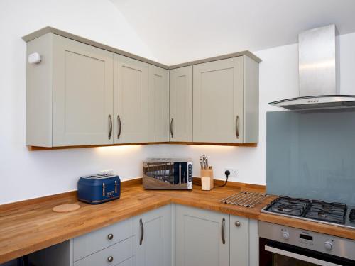 a kitchen with white cabinets and a wooden counter top at Pass the Keys Stylish 2 Bed Flat near Beach M5 in Burnham on Sea