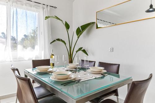 a dining room with a table with chairs and a plant at Limnaria Gardens Beautiful Apartment by VICHY in Paphos