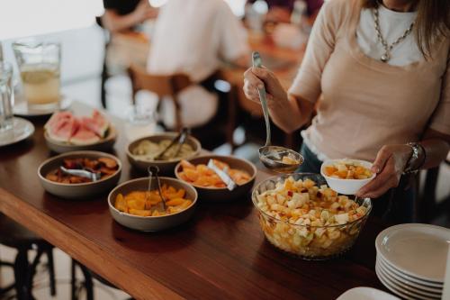 a woman standing at a table with bowls of food at La Urumpta Hotel, AKEN MIND in Río Cuarto