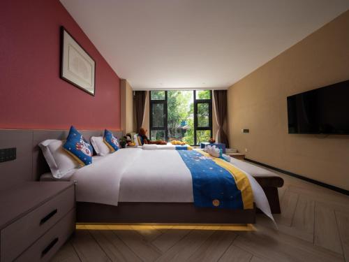 a bedroom with a large bed and a television at Yun Guan Shunde Renjia Resort Hotel in Jinghong