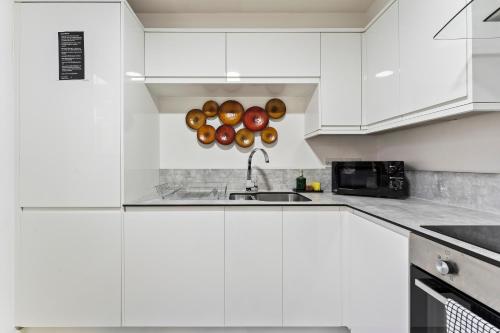 a kitchen with white cabinets and a sink and somenuts at Bloom Court -Sleeps 6-Free Parking with Workspace & High-Speed WiFi in Birmingham