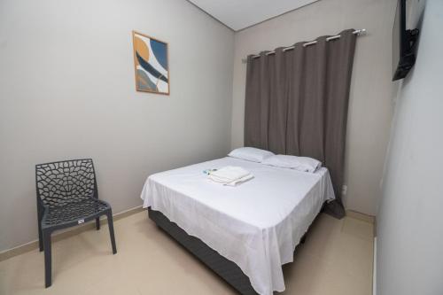 a small bedroom with a bed and a chair at Pousada Calugy in Jardim