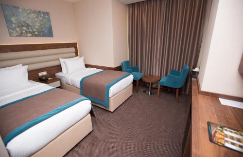 a hotel room with two beds and a table and chairs at Görükle Güler Park Hotel in Gorukle