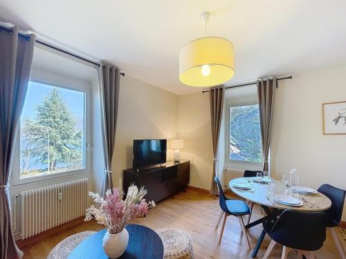 un salon avec une table, des chaises et une télévision dans l'établissement Le Cocon de Colmyr - Vue sur le lac - Parking privé, à Annecy