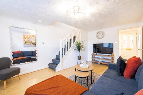 a living room with a blue couch and a tv at SionStays - Honeysuckle Court - Close to City Centre! in Peterborough