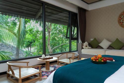a bedroom with a bed and a table with a bowl of fruit at Yun Guan Shunde Renjia Resort Hotel in Jinghong
