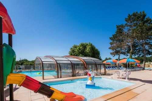 une piscine avec un toboggan aquatique dans un complexe hôtelier dans l'établissement Camping Les Truffières de Dordogne - Maeva, à Saint-Geniès