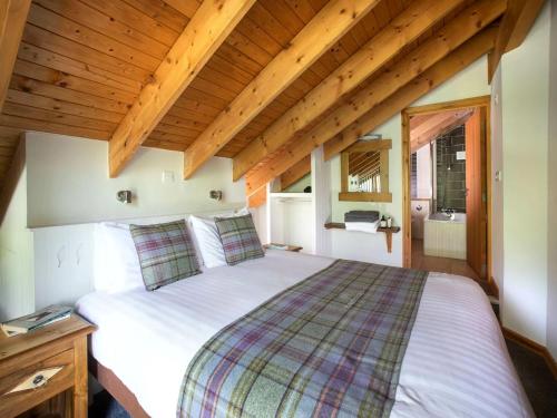 a bedroom with a large bed in a room with wooden ceilings at Strathyre, Ben Ledi Cabins - Forest Holidays in Callander