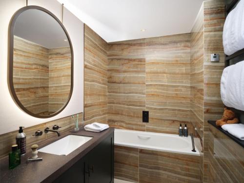 a bathroom with a tub and a sink and a mirror at The Other House South Kensington in London