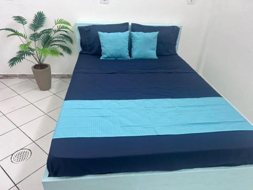 a blue bed with blue pillows and a plant at Vilarejo Tropical Itanhaem in Itanhaém
