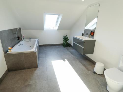 a bathroom with a tub and a toilet and a sink at Heron's Den in Horncastle