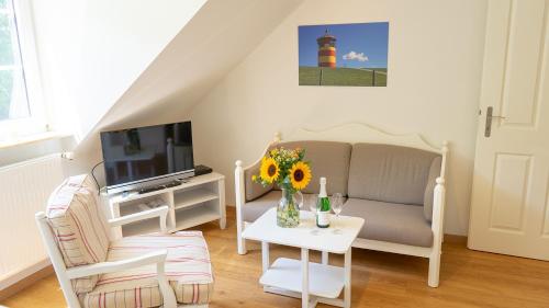 a living room with a couch and a tv and a table at Dreschdiele - Landlust Osterwarf in Norddeich