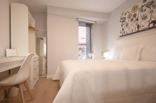 ein weißes Schlafzimmer mit einem weißen Bett und einem Schreibtisch in der Unterkunft LC Apartaments Fleming Moderno&Ubicación ideal I 3 Hab dobles I aire acondicionado in Castellón de la Plana